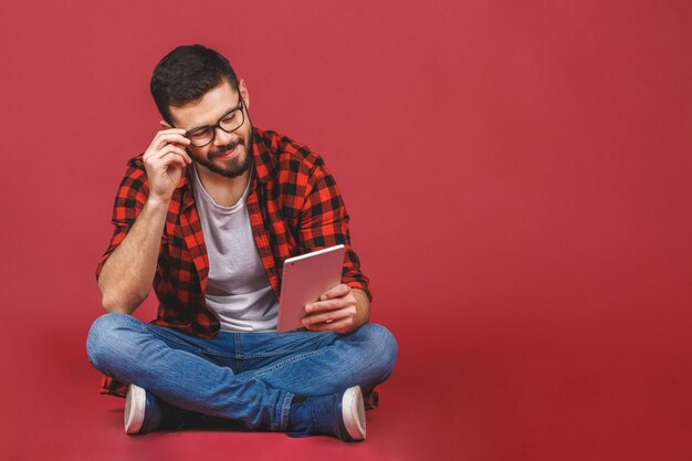 Portrait of young man sitting on the floor using a tablet