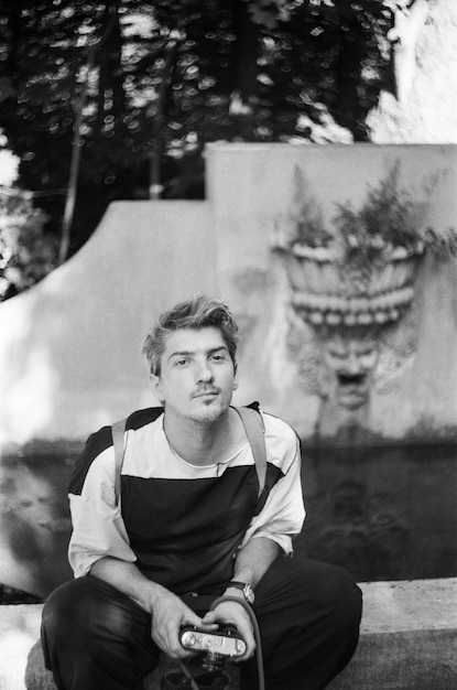 Portrait of young man sitting on a fountain