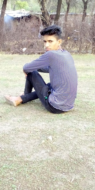 Photo portrait of young man sitting on grass