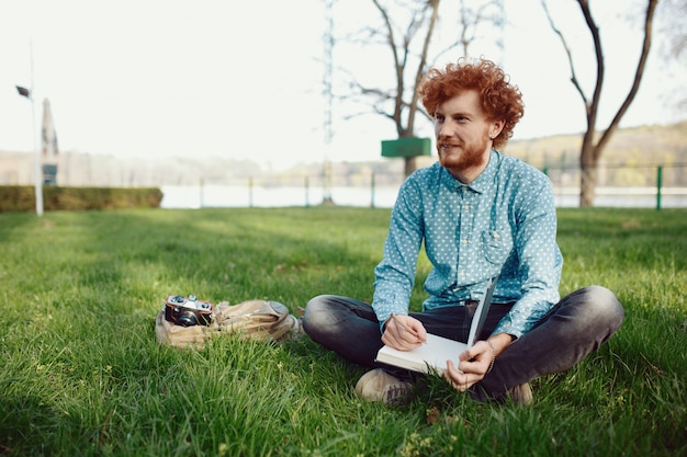 Photo portrait of a young man sitting on a green meadow grass