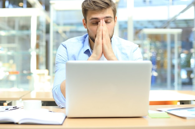 Portrait of young man sitting at his desk in the office.