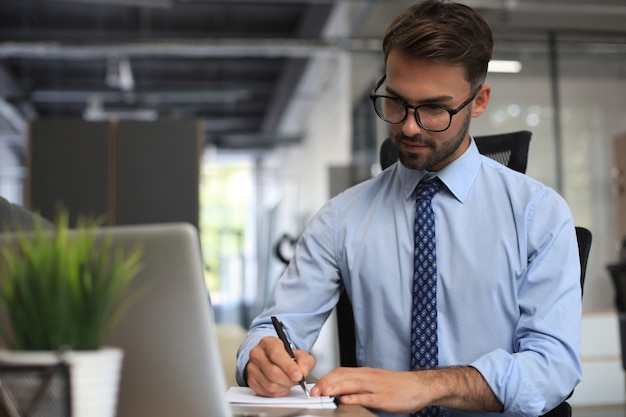 Photo portrait of young man sitting at his desk in the office.