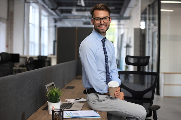 Photo portrait of young man sitting at his desk in the office.