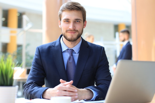 Photo portrait of young man sitting at his desk in the office.