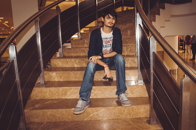 Photo portrait of young man sitting on staircase