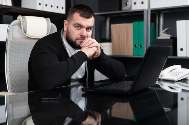 Portrait of young man sitting at table in office