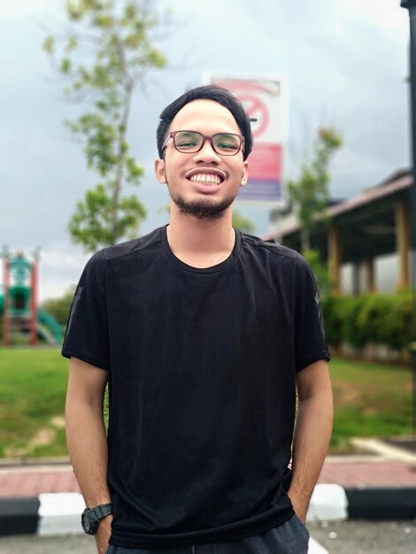 Portrait of young man smiling while standing against city