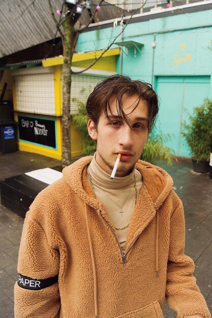 Photo portrait of young man smoking cigarette on footpath