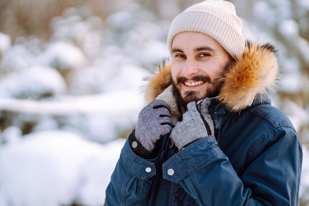 Portrait of young man in snowy winter forest Season christmas travel and people concept