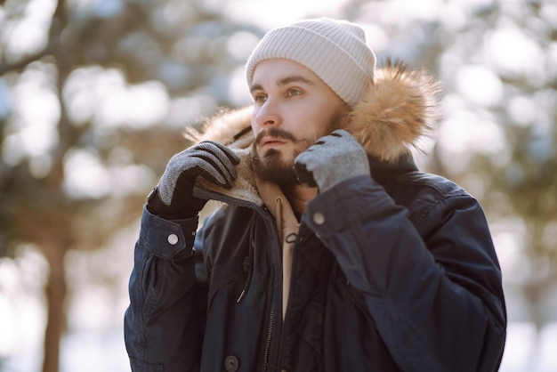 Portrait of young man in snowy winter forest Season christmas travel and people concept