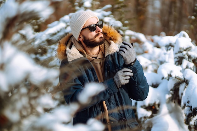 Portrait of young man in snowy winter forest Season christmas travel and people concept