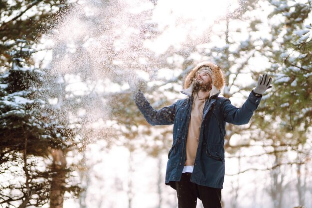 Portrait of young man in snowy winter forest Season christmas travel and people concept