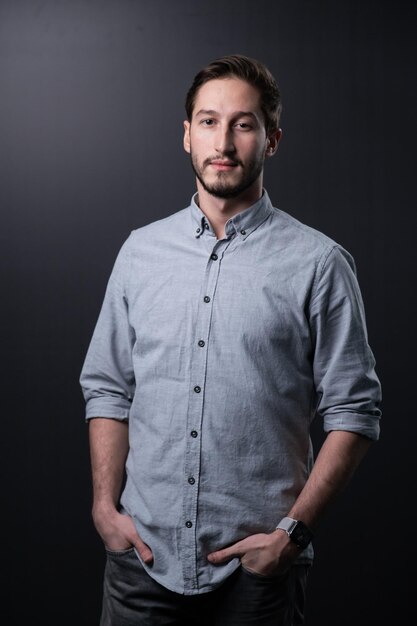 Portrait of young man standing against black background