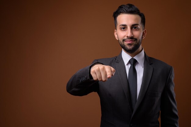 Portrait of young man standing against black background