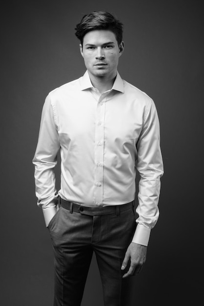 portrait of young man standing against black background