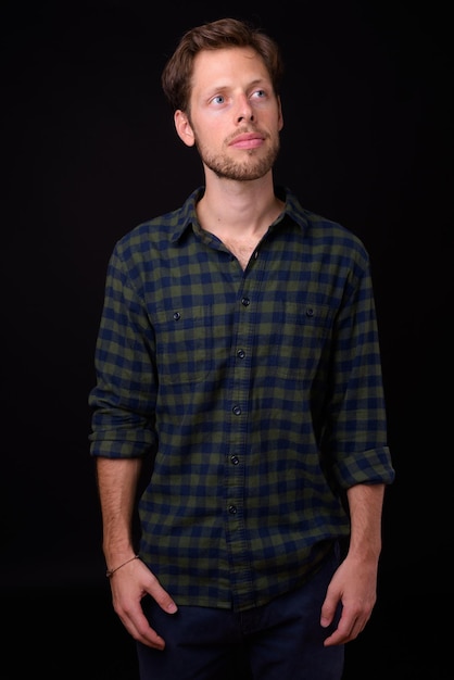 Photo portrait of young man standing against black background