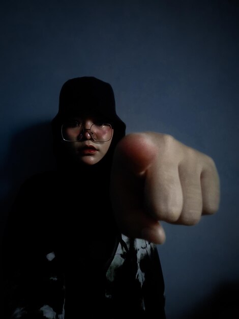 Portrait of young man standing against black background