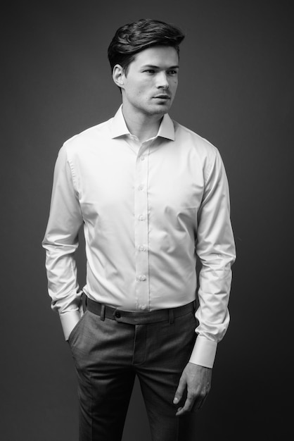 portrait of young man standing against black background