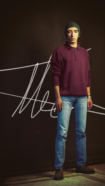 Portrait of young man standing against black background