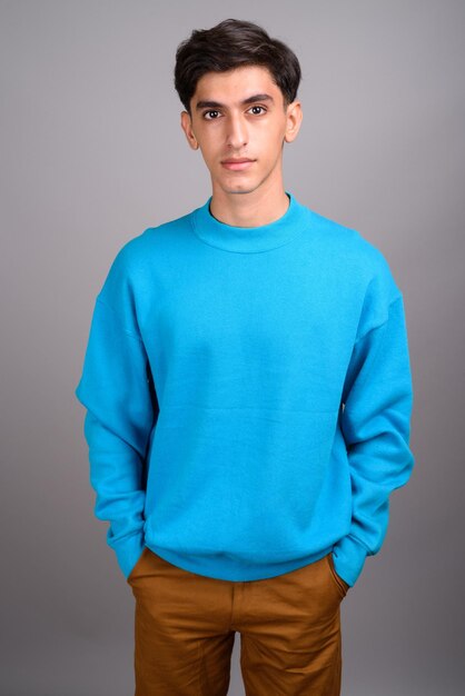 Portrait of young man standing against blue background