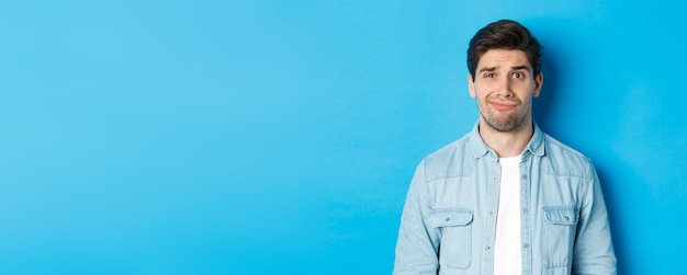 Portrait of young man standing against blue background