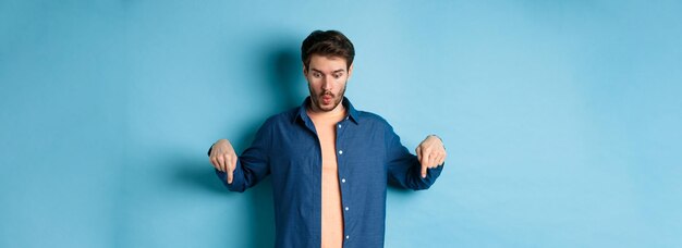 Portrait of young man standing against blue background