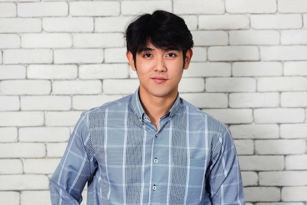 portrait of young man standing against brick wall