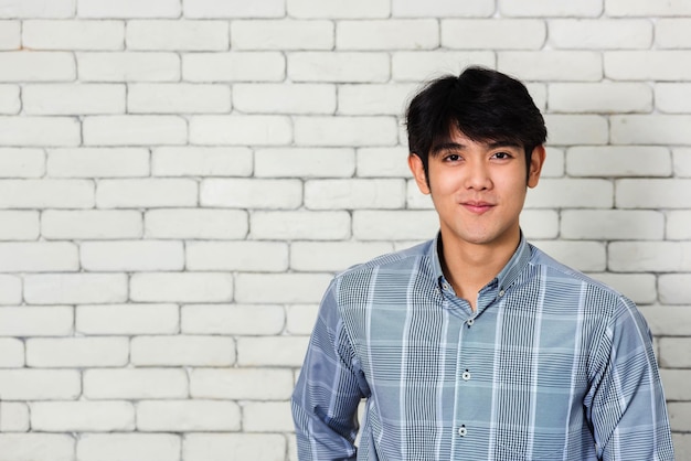portrait of young man standing against brick wall