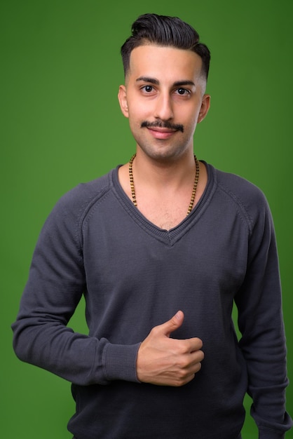 Portrait of young man standing against gray background