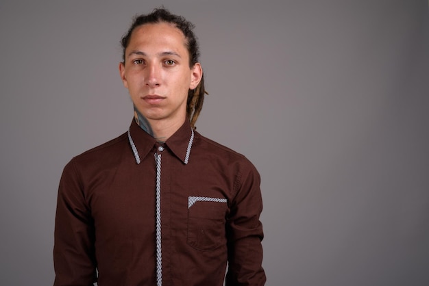 Portrait of young man standing against gray background