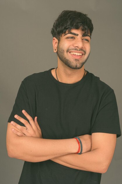 Portrait of young man standing against gray background