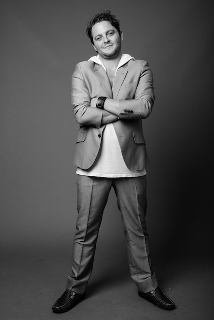 Portrait of young man standing against gray background