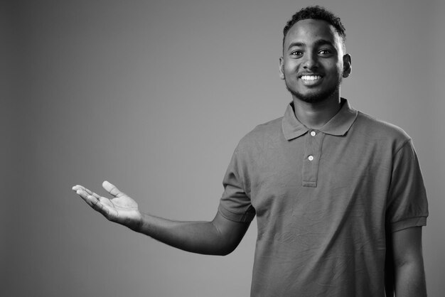 Portrait of young man standing against gray background