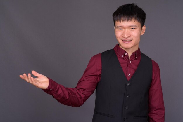 Portrait of young man standing against gray background