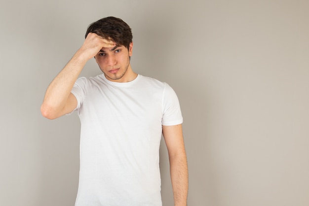 Portrait of a young man standing against gray.