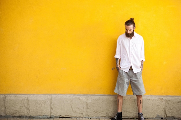 Portrait of young man standing against orange wall