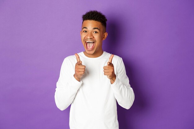 Portrait of young man standing against purple background