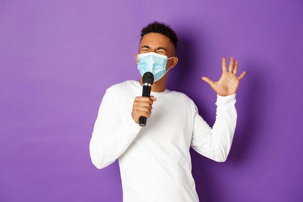 Portrait of young man standing against purple background