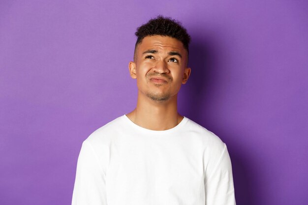 Portrait of young man standing against purple background