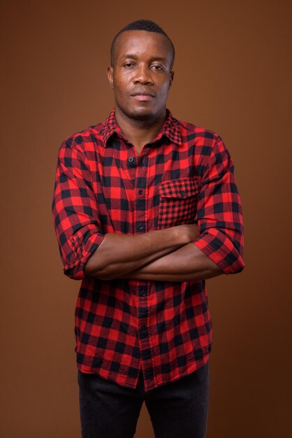 Portrait of young man standing against red background