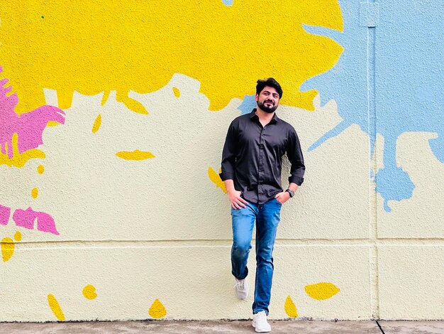 Portrait of young man standing against wall