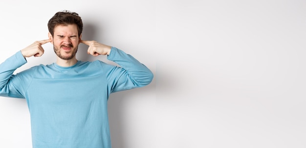 Portrait of young man standing against white background