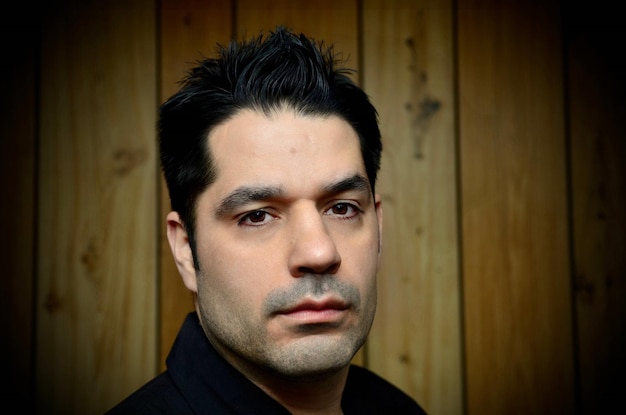 Portrait of young man standing against wooden wall