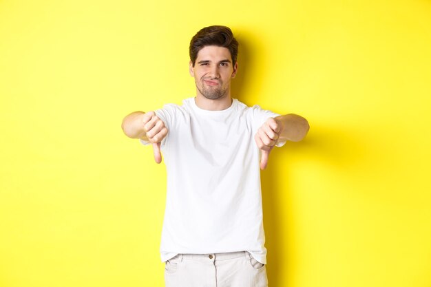 Portrait of young man standing against yellow background