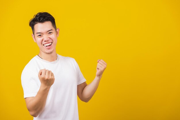 Portrait of young man standing against yellow background