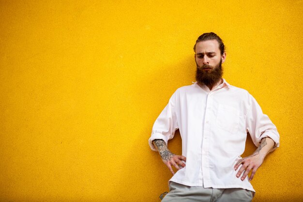 Portrait of young man standing against yellow wall