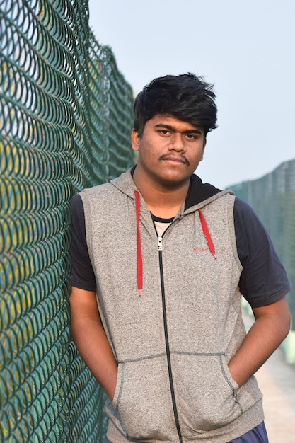 Photo portrait of young man standing by fence