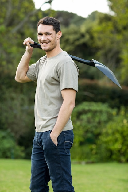 Portrait of young man standing in garden with a gardening shovel in garden