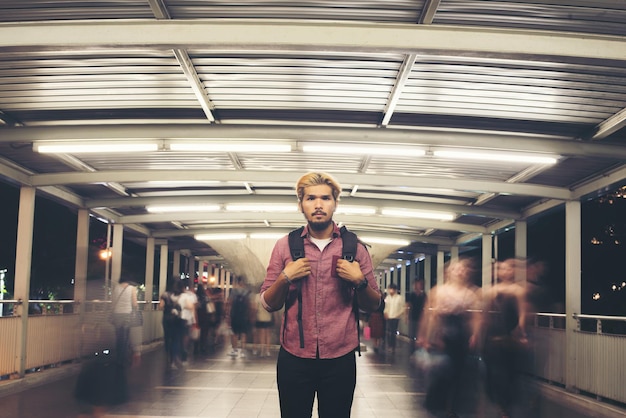 Photo portrait of young man standing on illuminated footbridge at night