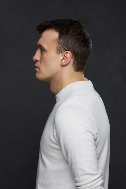 Portrait of a young man in the studio on a black background. Side profile.